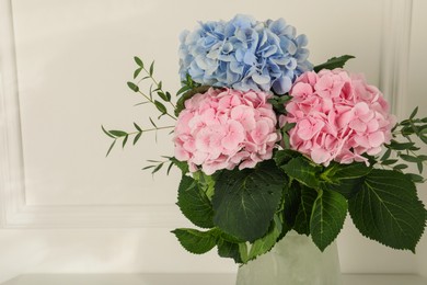 Beautiful hortensia flowers in vase near white wall. Space for text Photo of Beautiful hortensia flowers in vase near white wall. Space for text