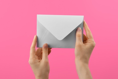 Woman holding white paper envelope on pink background, closeup Photo of Woman holding white paper envelope on pink background, closeup
