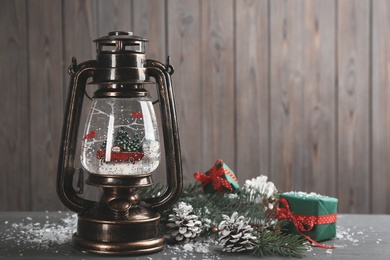 Beautiful snow globe in vintage lantern, gifts and Christmas decor on grey wooden table. Space for text Photo of Beautiful snow globe in vintage lantern, gifts and Christmas decor on grey wooden table. Space for text