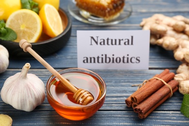 Different fresh products and card with phrase Natural Antibiotic on blue wooden table Photo of Different fresh products and card with phrase Natural Antibiotic on blue wooden table