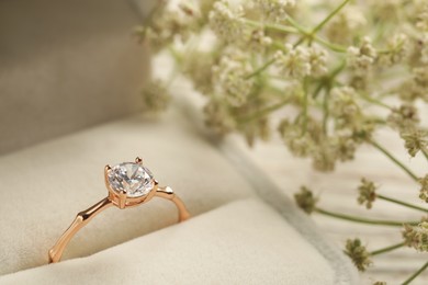 Beautiful engagement ring with gemstone in box and flowers on table, closeup Photo of Beautiful engagement ring with gemstone in box and flowers on table, closeup