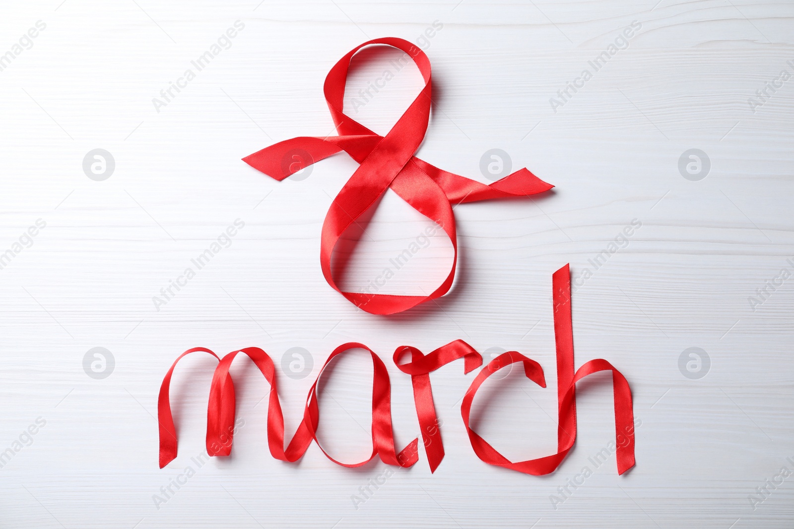8 March greeting card design with red ribbon on white wooden background, flat lay. International Women's day Photo of 8 March greeting card design with red ribbon on white wooden background, flat lay. International Women's day