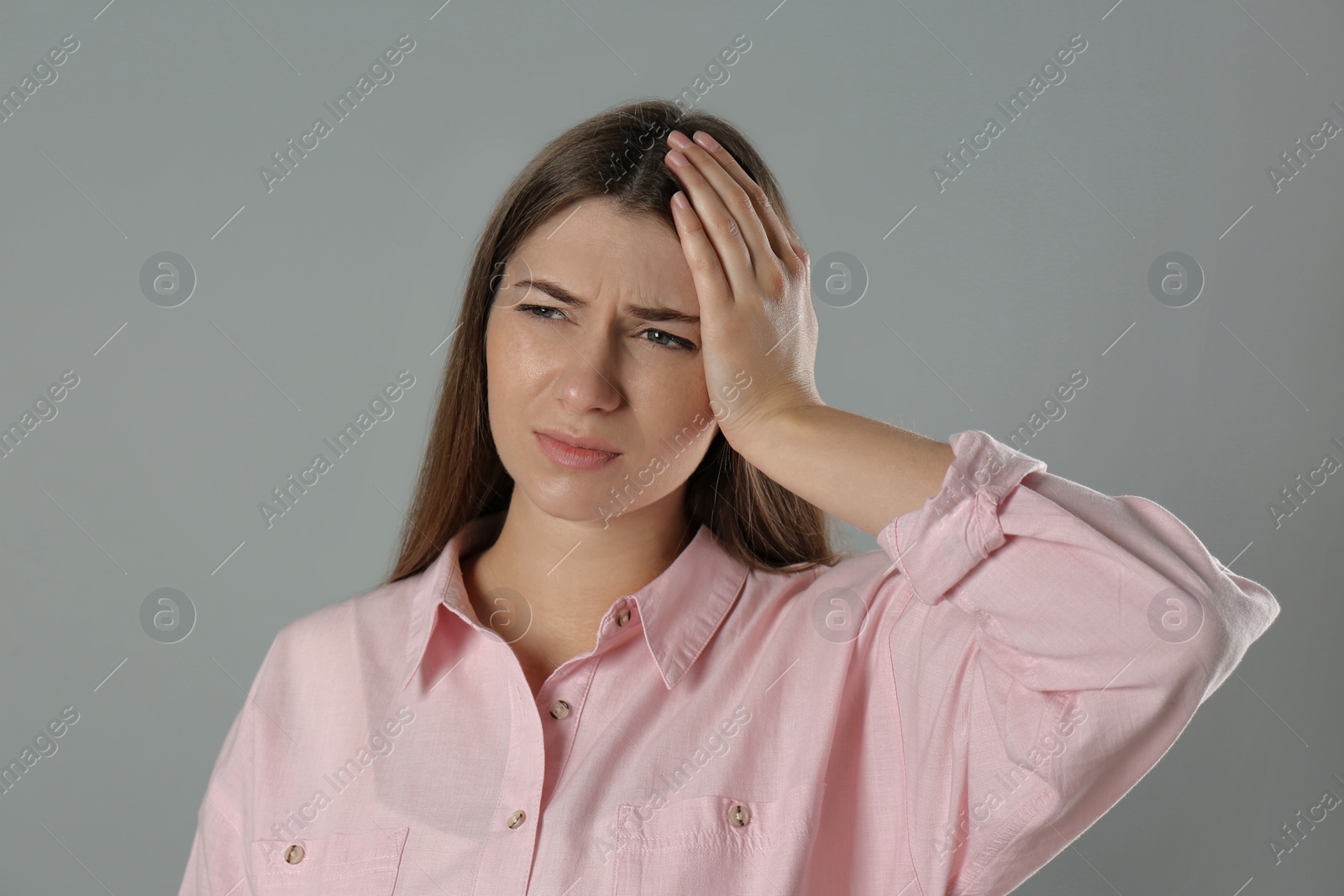 Young woman suffering from migraine on grey background Photo of Young woman suffering from migraine on grey background