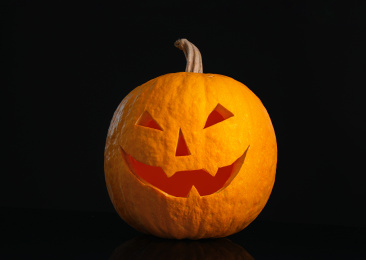 Pumpkin with scary face on black background. Halloween traditional decor Photo of Pumpkin with scary face on black background. Halloween traditional decor