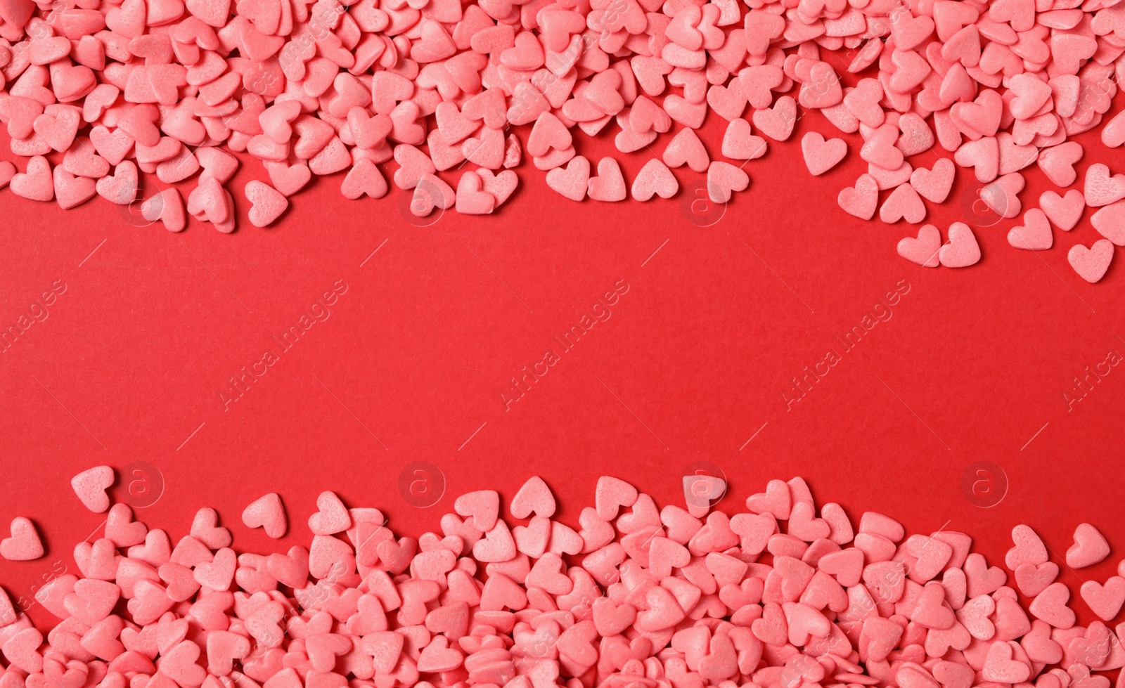 Bright heart shaped sprinkles on red background, flat lay. Space for text Photo of Bright heart shaped sprinkles on red background, flat lay. Space for text
