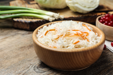 Photo of Tasty fermented cabbage on wooden table, closeup