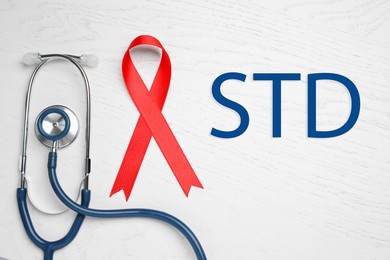 Red awareness ribbon, stethoscope and abbreviation STD on white wooden background, flat lay Image of Red awareness ribbon, stethoscope and abbreviation STD on white wooden background, flat lay