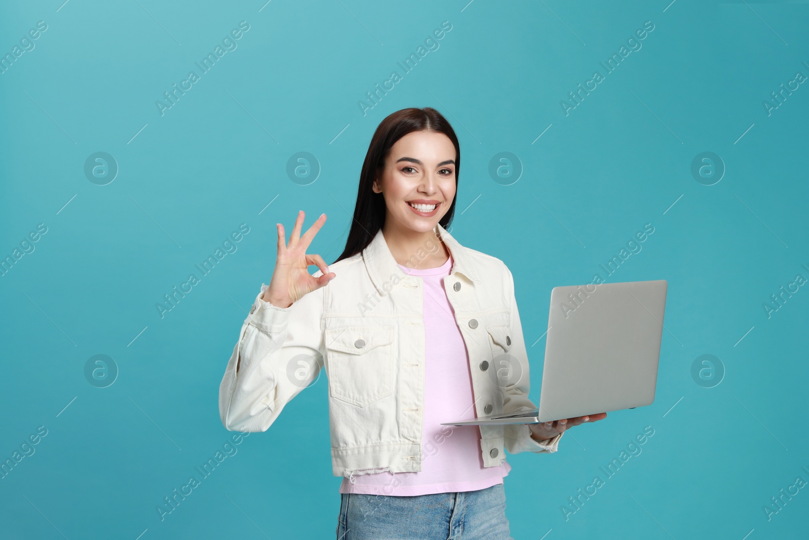 Young woman with modern laptop on light blue background Photo of Young woman with modern laptop on light blue background