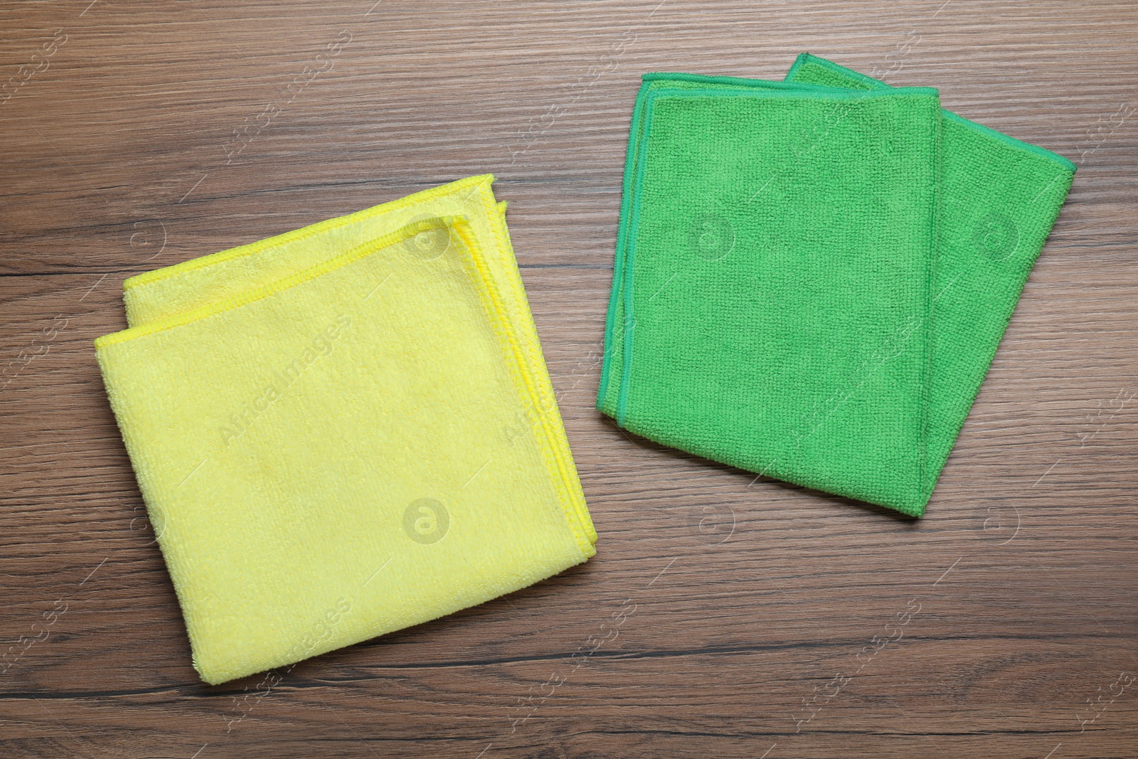 Green and yellow microfiber cloths on wooden table, flat lay Photo of Green and yellow microfiber cloths on wooden table, flat lay