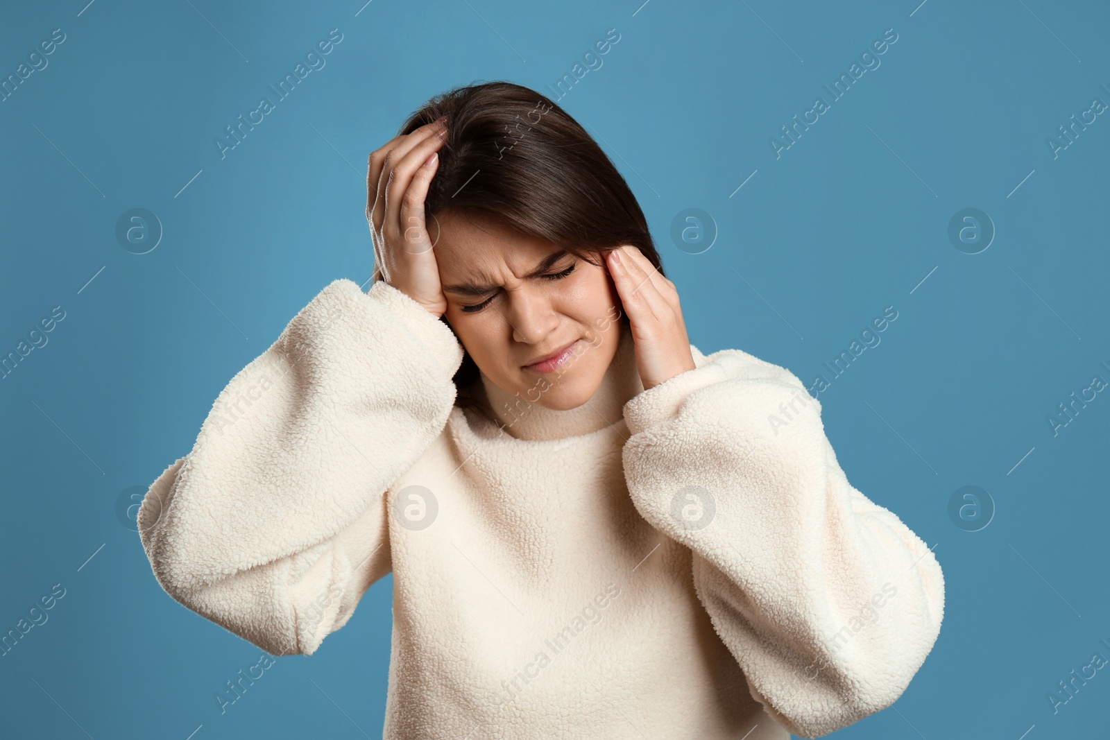 Young woman suffering from migraine on light blue background Photo of Young woman suffering from migraine on light blue background