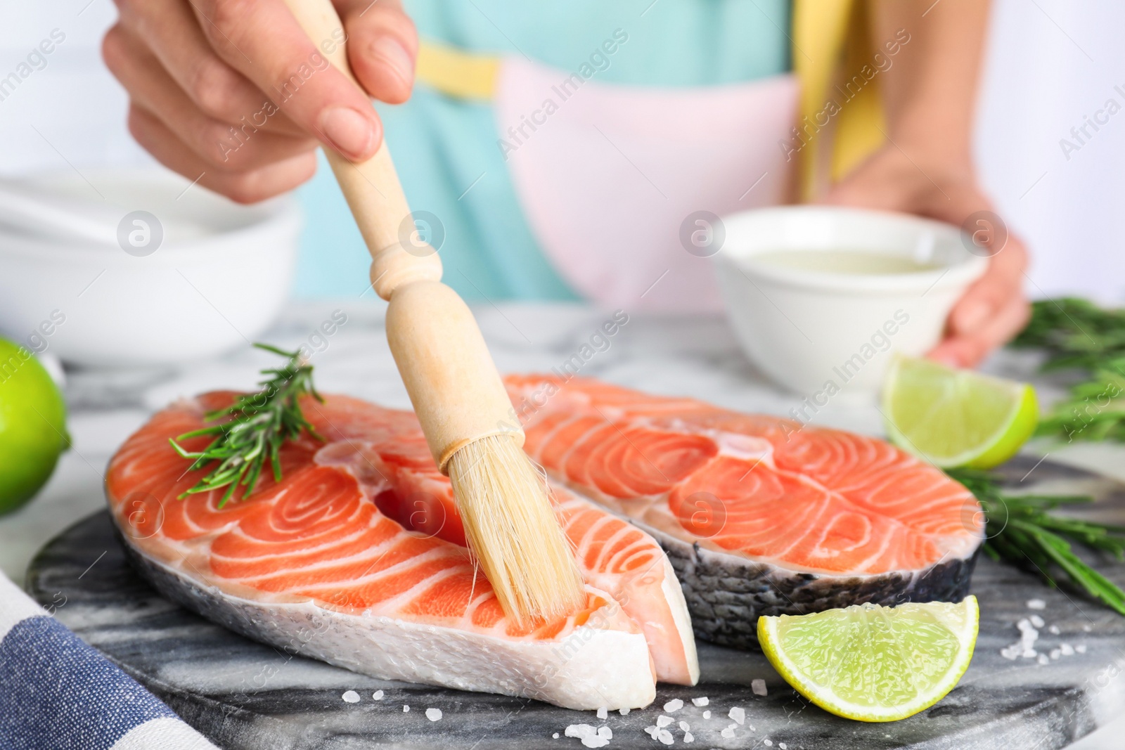 Woman marinating fresh raw salmon at table, closeup. Fish delicacy Photo of Woman marinating fresh raw salmon at table, closeup. Fish delicacy
