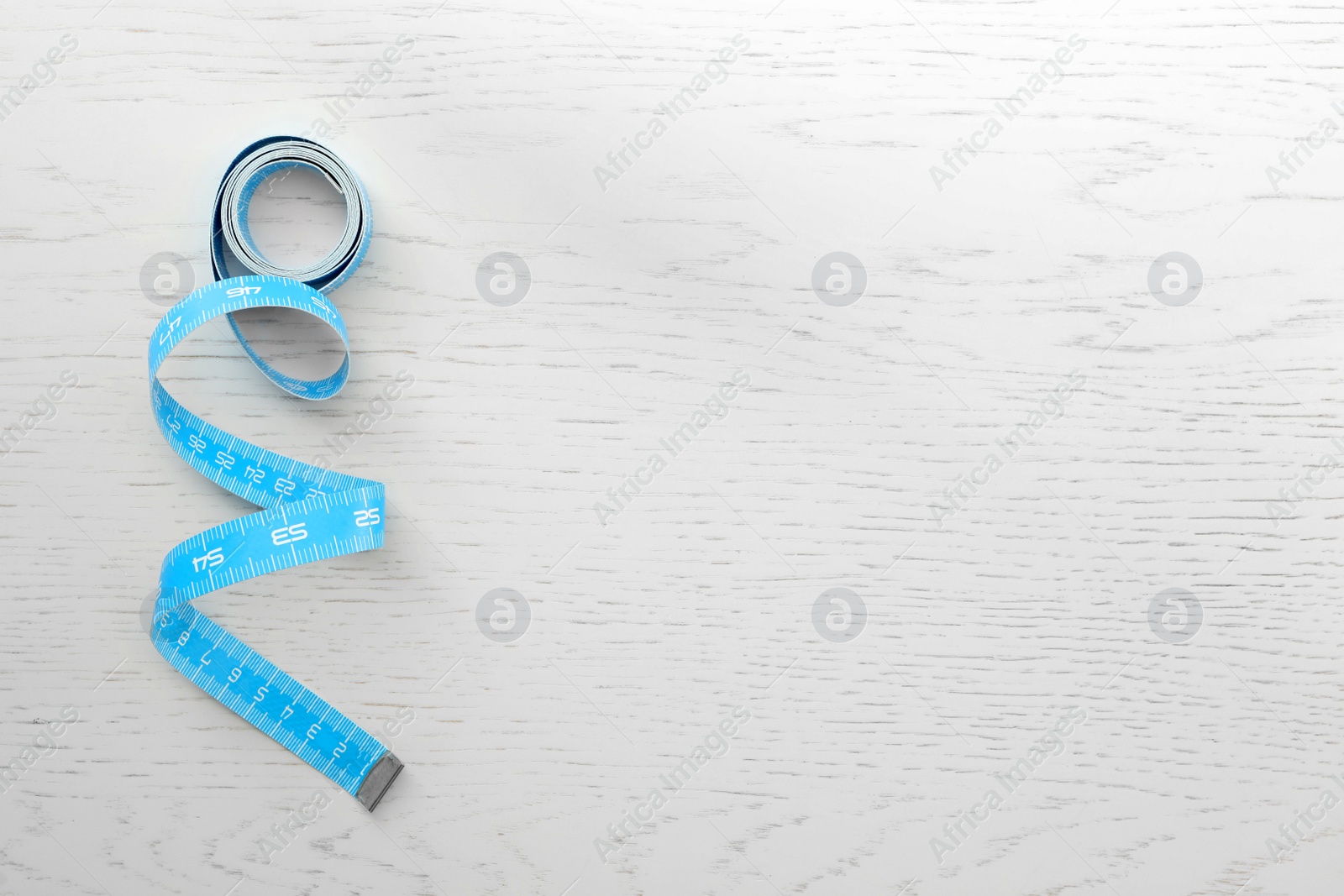 light blue measuring tape on white wooden table, top view. Space for text Photo of light blue measuring tape on white wooden table, top view. Space for text