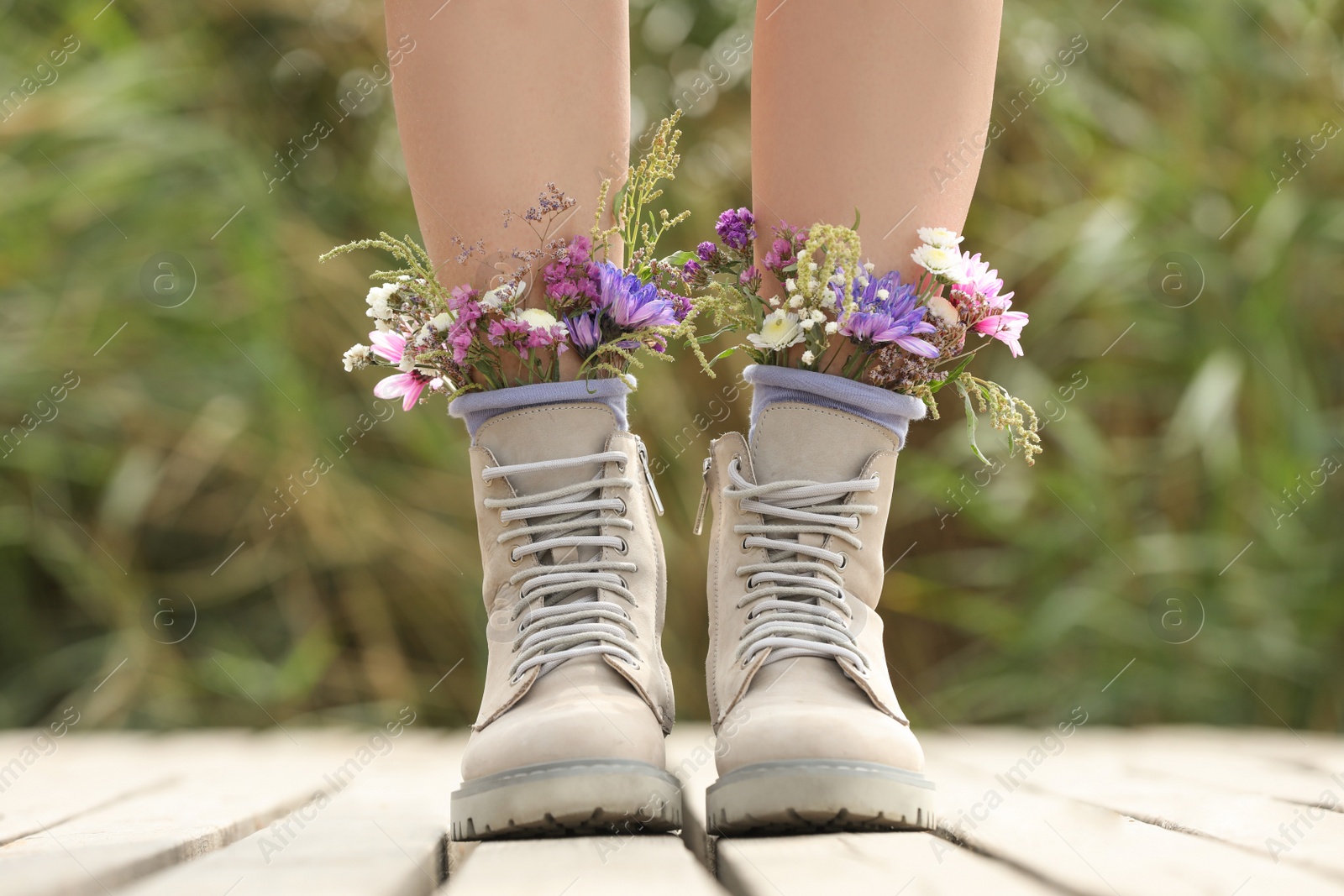 Woman standing on wooden pier with flowers in socks outdoors, closeup Photo of Woman standing on wooden pier with flowers in socks outdoors, closeup