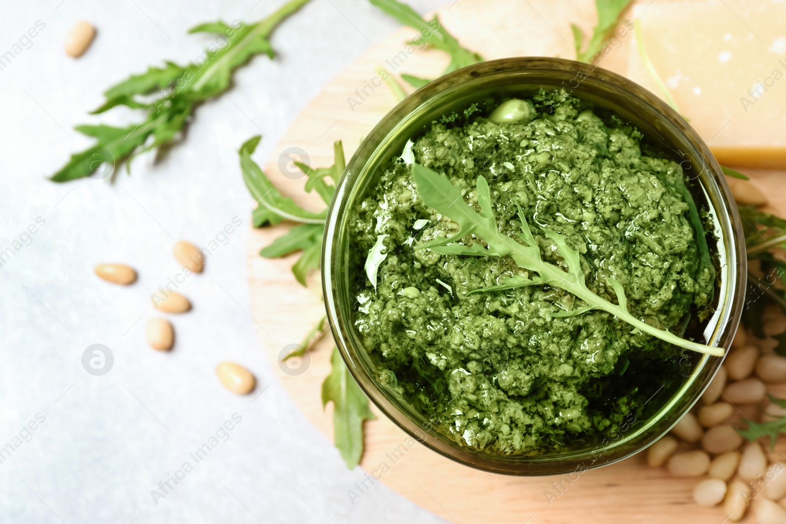 Bowl of tasty arugula pesto and ingredients on light table, flat lay Photo of Bowl of tasty arugula pesto and ingredients on light table, flat lay