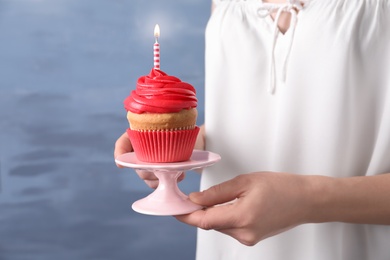 Woman holding stand with birthday cupcake on blurred background Photo of Woman holding stand with birthday cupcake on blurred background