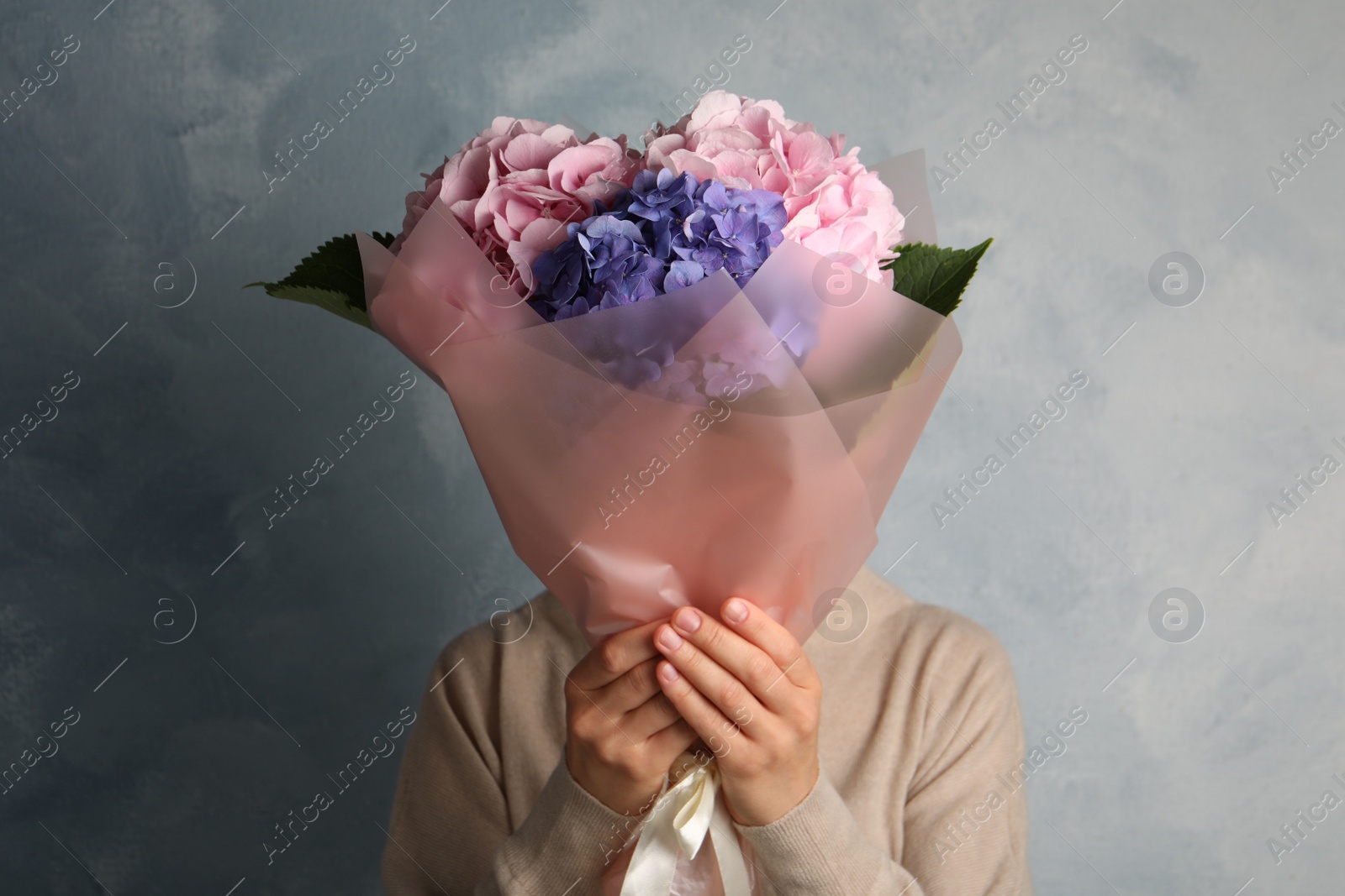 Woman with bouquet of beautiful hortensia flowers on color background Photo of Woman with bouquet of beautiful hortensia flowers on color background