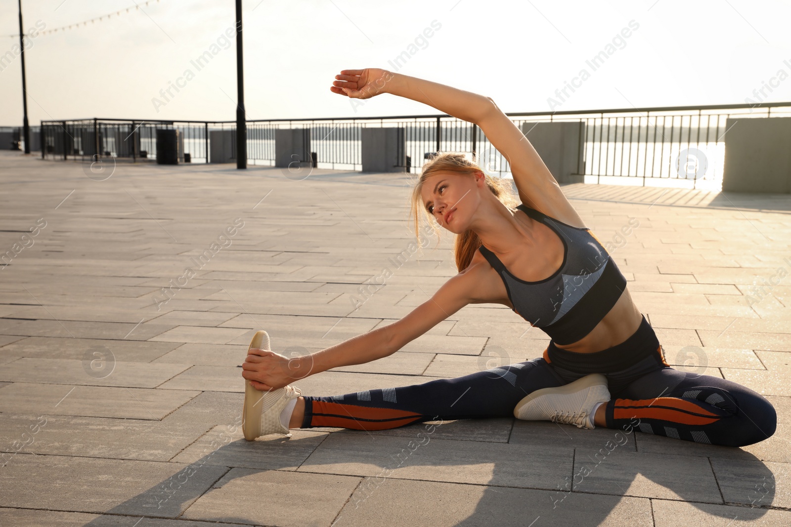 Beautiful woman in sportswear doing exercises outdoors on sunny day Photo of Beautiful woman in sportswear doing exercises outdoors on sunny day