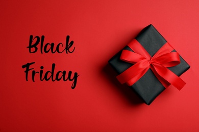 Phrase Black Friday and gift box on red background, top view Photo of Phrase Black Friday and gift box on red background, top view