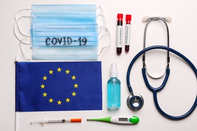 Flat lay composition with European Union flag and protective masks on white background. Coronavirus outbreak Photo of Flat lay composition with European Union flag and protective masks on white background. Coronavirus outbreak