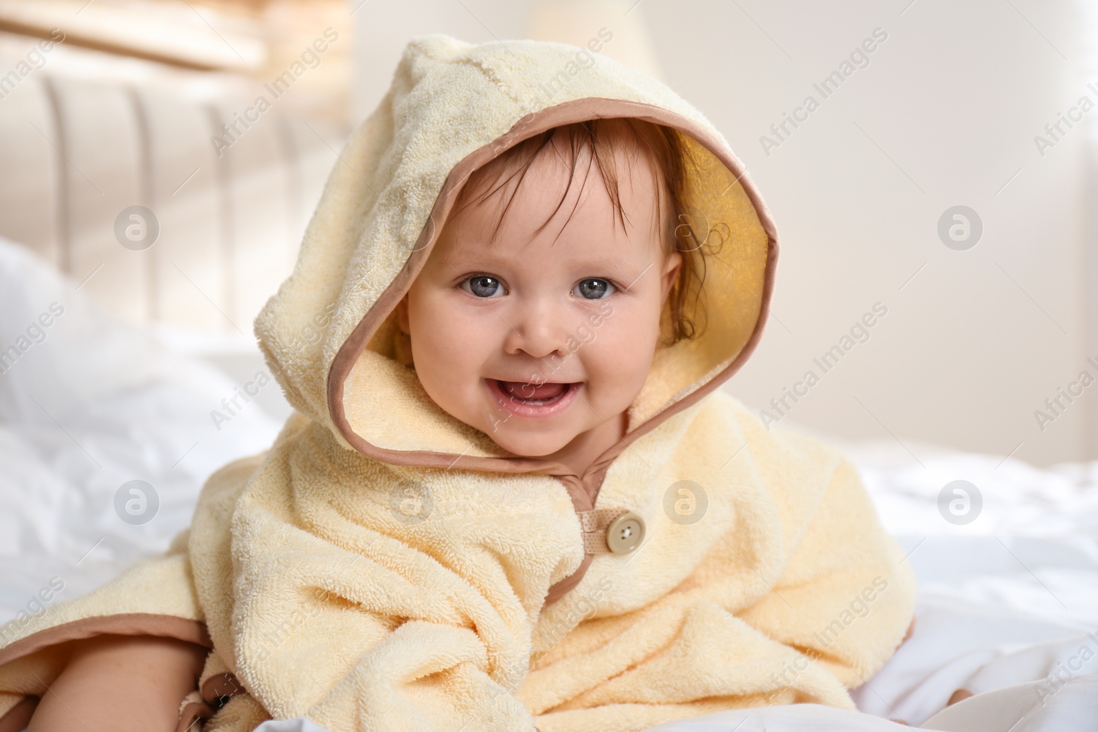 Cute little baby in yellow hooded towel on bed after bath Photo of Cute little baby in yellow hooded towel on bed after bath