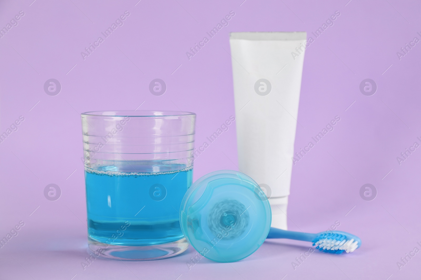 Mouthwash, toothbrush, paste and dental floss on violet background Photo of Mouthwash, toothbrush, paste and dental floss on violet background