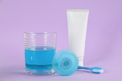 Mouthwash, toothbrush, paste and dental floss on violet background Photo of Mouthwash, toothbrush, paste and dental floss on violet background