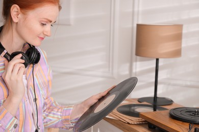 Young woman with vinyl disc near turntable at home Photo of Young woman with vinyl disc near turntable at home