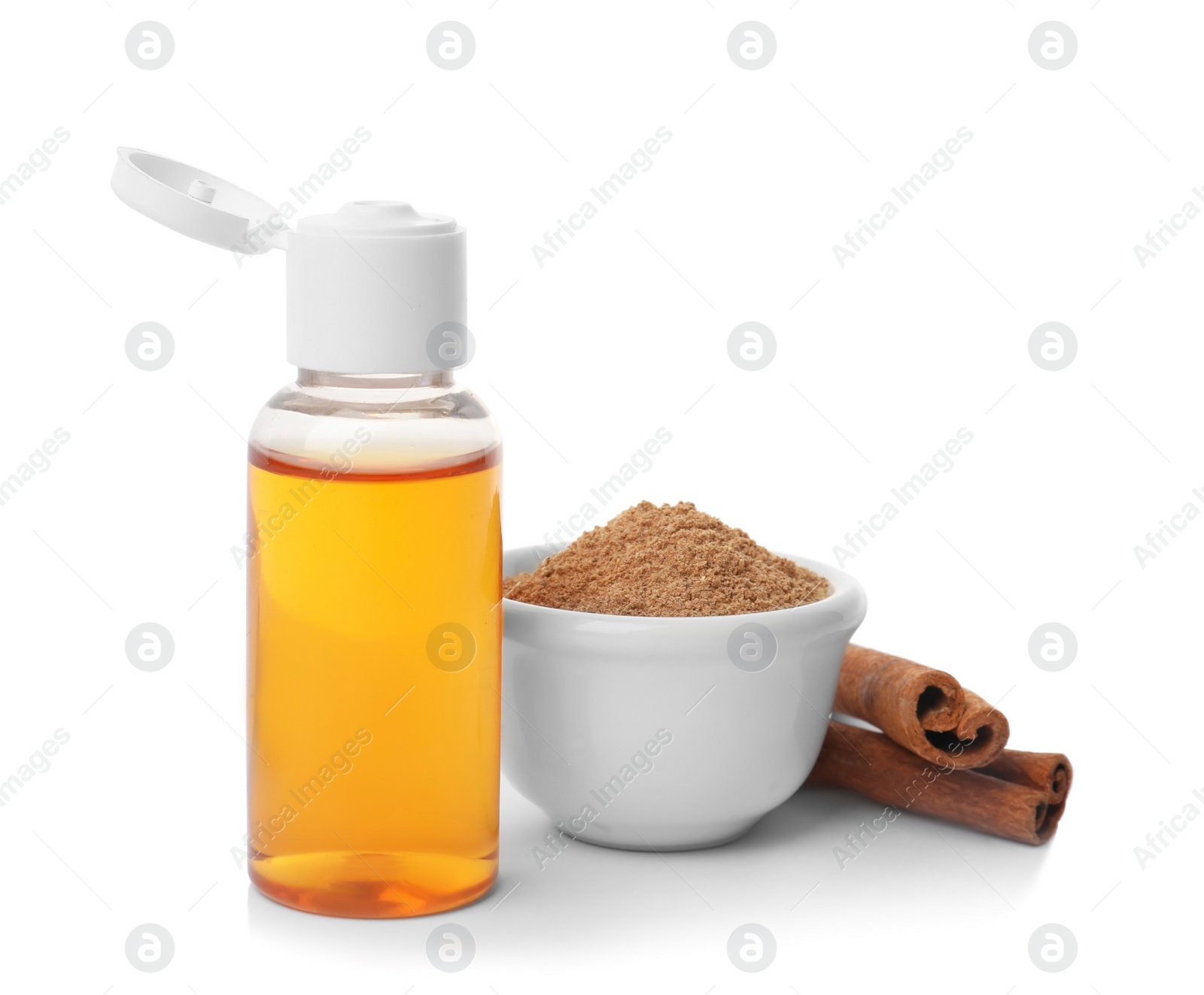 Bottle of cinnamon oil, bowl with powder and sticks on white background Photo of Bottle of cinnamon oil, bowl with powder and sticks on white background
