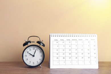 Calendar and alarm clock on wooden table against beige background Image of Calendar and alarm clock on wooden table against beige background