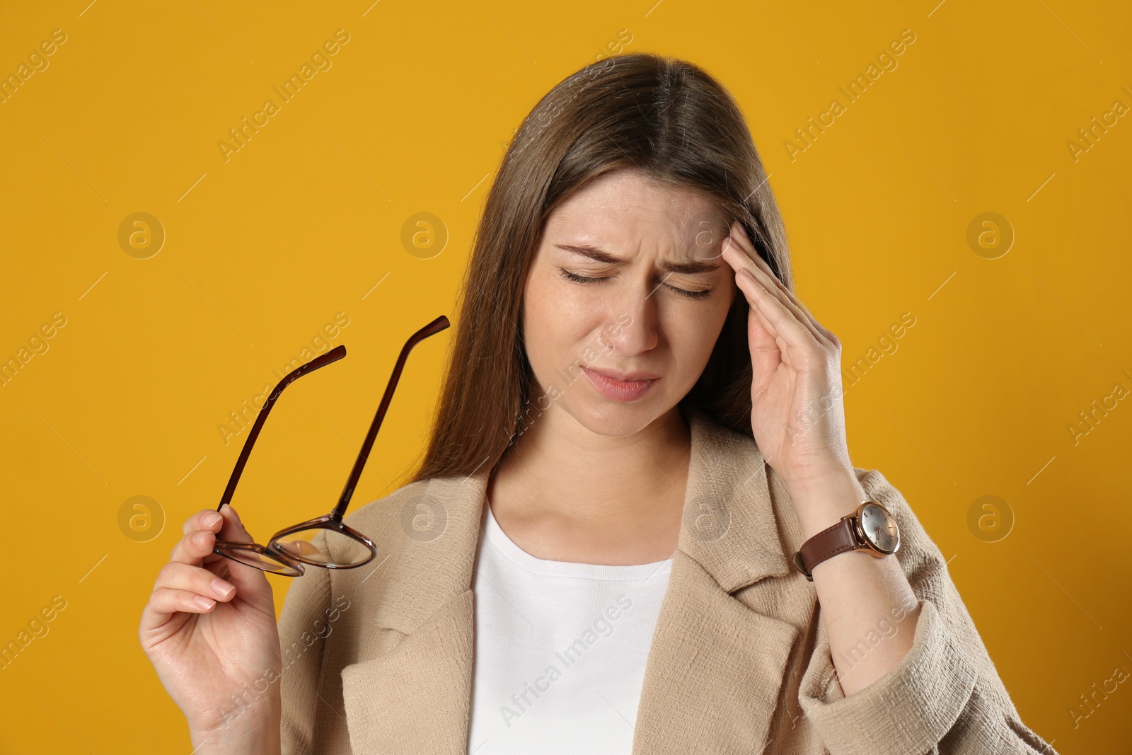 Young woman suffering from migraine on yellow background Photo of Young woman suffering from migraine on yellow background