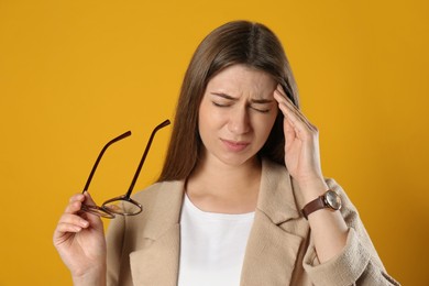 Young woman suffering from migraine on yellow background Photo of Young woman suffering from migraine on yellow background
