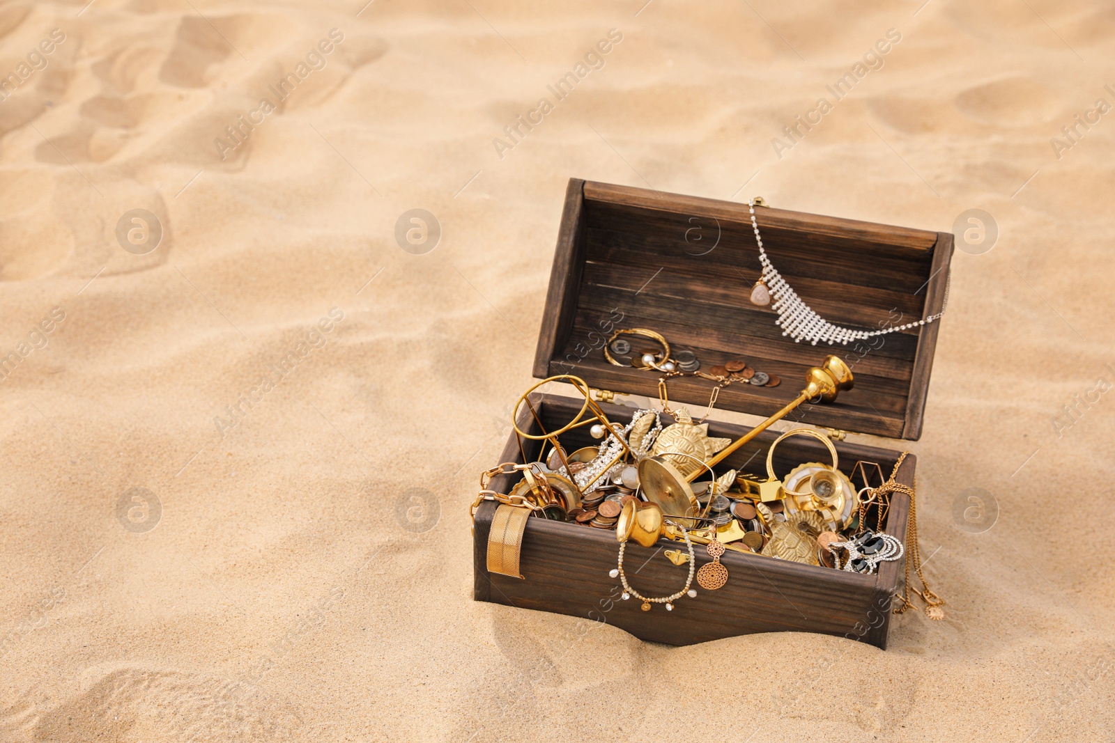 Open wooden treasure chest on sand, space for text Photo of Open wooden treasure chest on sand, space for text