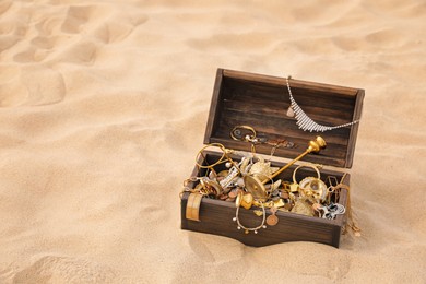 Open wooden treasure chest on sand, space for text Photo of Open wooden treasure chest on sand, space for text