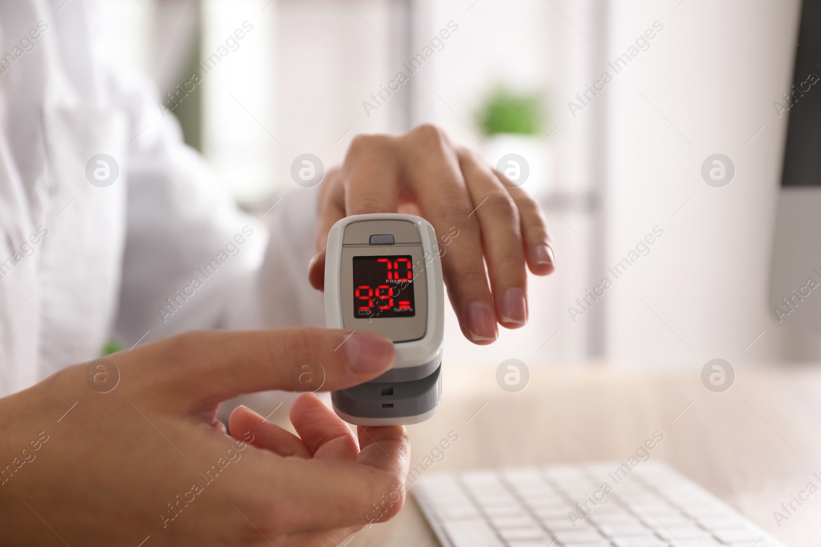 Woman measuring oxygen level with modern fingertip pulse oximeter at workplace, closeup Photo of Woman measuring oxygen level with modern fingertip pulse oximeter at workplace, closeup