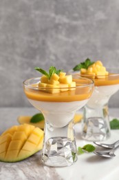 Delicious panna cotta with mango coulis served on light grey table Photo of Delicious panna cotta with mango coulis served on light grey table