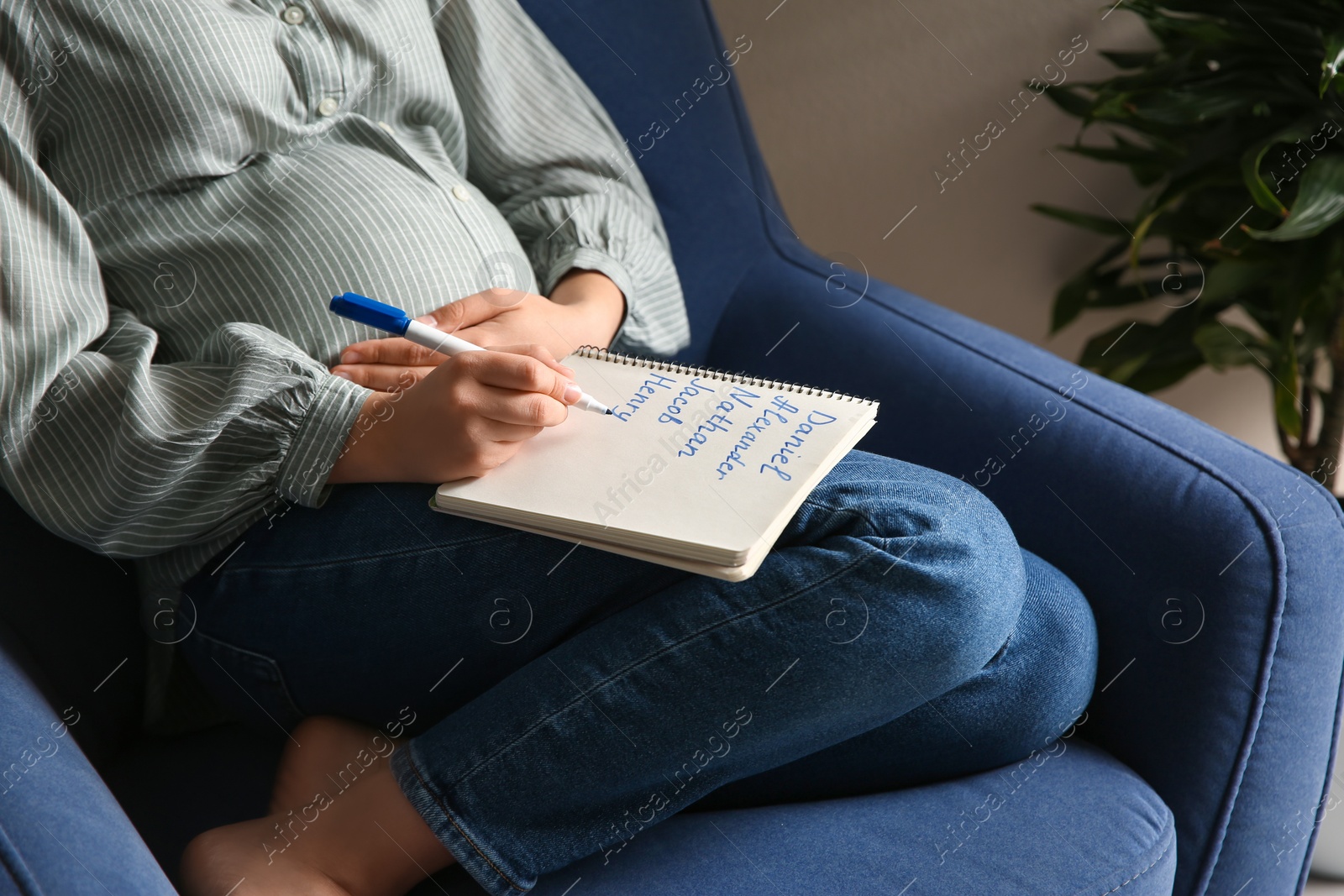 Pregnant woman with baby names list sitting in armchair, closeup Photo of Pregnant woman with baby names list sitting in armchair, closeup