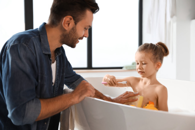 Photo of Young father with cute little daughter in bathroom