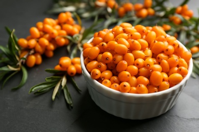 Fresh ripe sea buckthorn in bowl on black table, closeup Photo of Fresh ripe sea buckthorn in bowl on black table, closeup