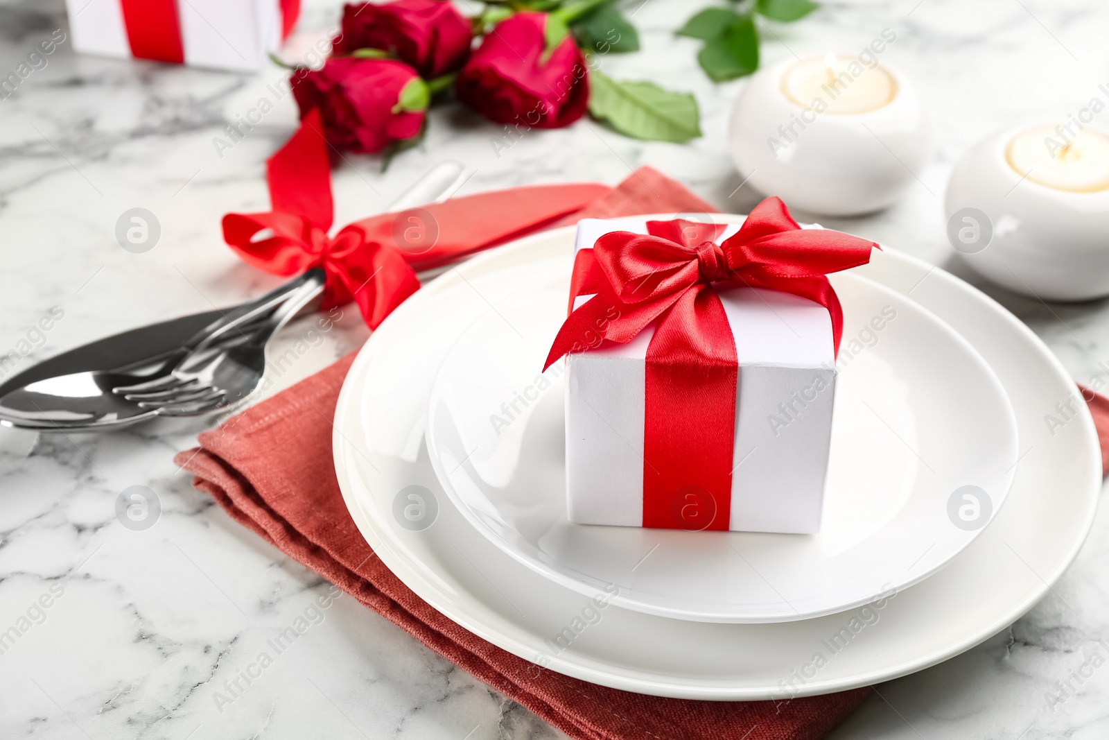 Beautiful table setting for Valentine's Day dinner with gift box on white marble background Photo of Beautiful table setting for Valentine's Day dinner with gift box on white marble background