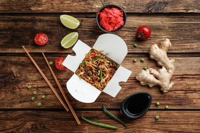 Box of wok noodles with vegetables and meat on wooden table, flat lay Photo of Box of wok noodles with vegetables and meat on wooden table, flat lay
