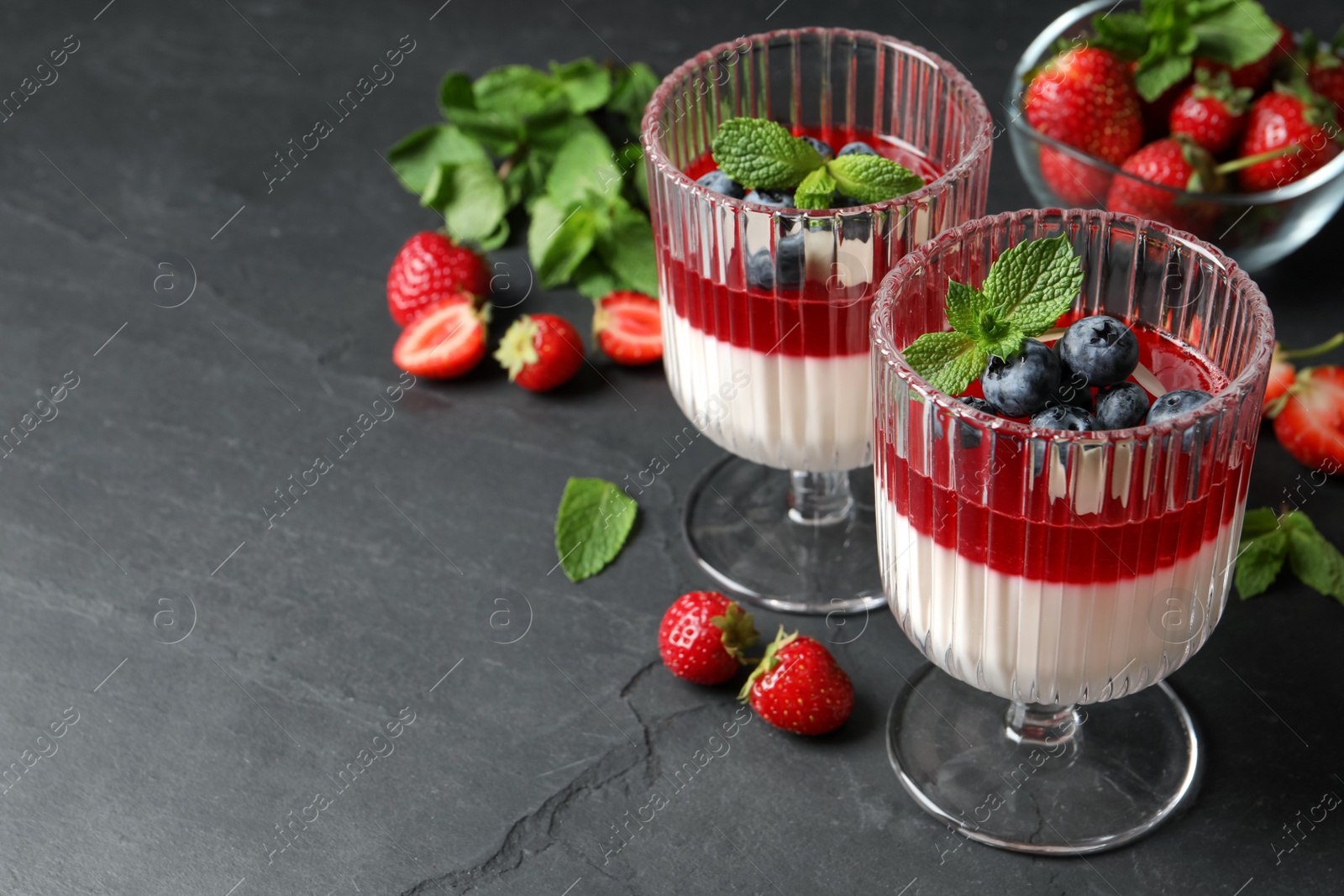 Delicious panna cotta with fruit coulis and fresh berries on dark grey table. Space for text Photo of Delicious panna cotta with fruit coulis and fresh berries on dark grey table. Space for text