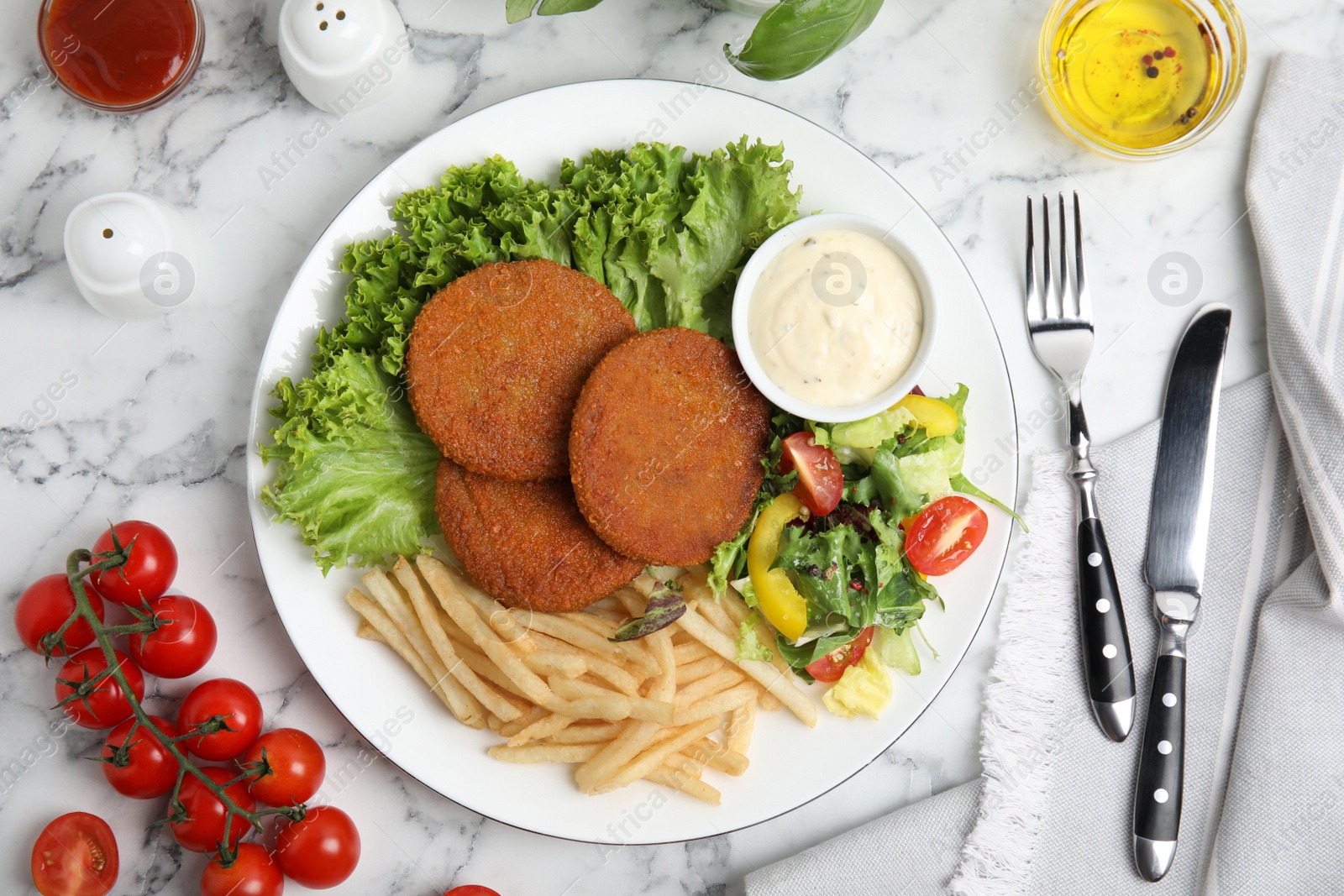Delicious fried breaded cutlets with garnish served on white marble table, flat lay Photo of Delicious fried breaded cutlets with garnish served on white marble table, flat lay