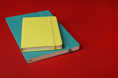 New stylish bright planners on red background Photo of New stylish bright planners on red background