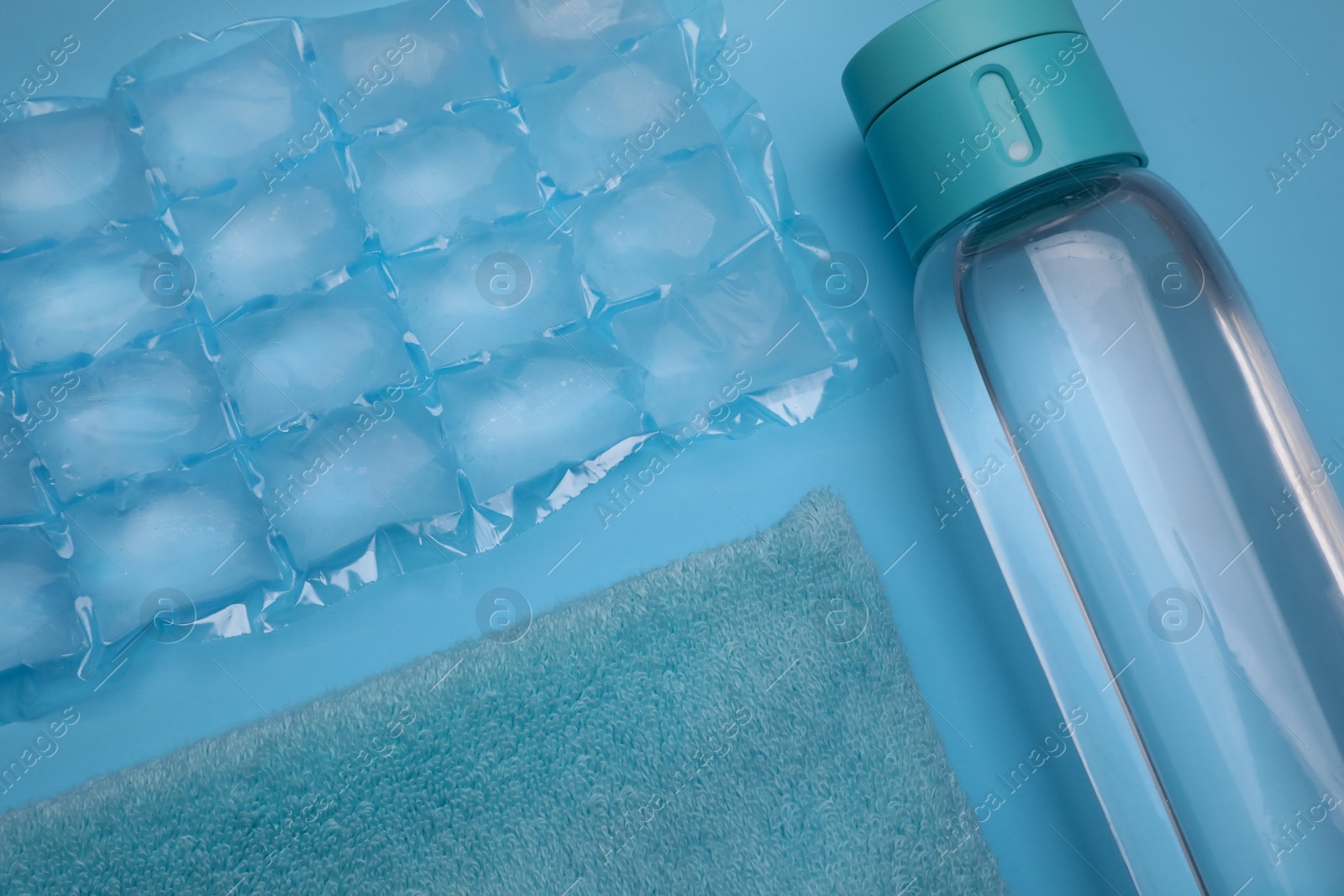 Bottle of water, ice pack and towel on light blue background, flat lay. Heat stroke treatment Photo of Bottle of water, ice pack and towel on light blue background, flat lay. Heat stroke treatment