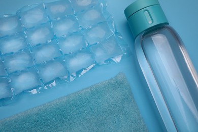Bottle of water, ice pack and towel on light blue background, flat lay. Heat stroke treatment Photo of Bottle of water, ice pack and towel on light blue background, flat lay. Heat stroke treatment