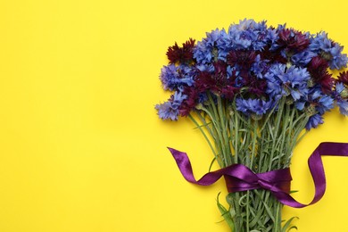 Bouquet of beautiful colorful cornflowers on yellow background, top view. Space for text Photo of Bouquet of beautiful colorful cornflowers on yellow background, top view. Space for text