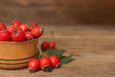 Ripe rose hip berries with green leaves on wooden table, closeup. Space for text Photo of Ripe rose hip berries with green leaves on wooden table, closeup. Space for text