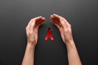 Woman with red awareness ribbon on black background, top view. World AIDS disease day Photo of Woman with red awareness ribbon on black background, top view. World AIDS disease day