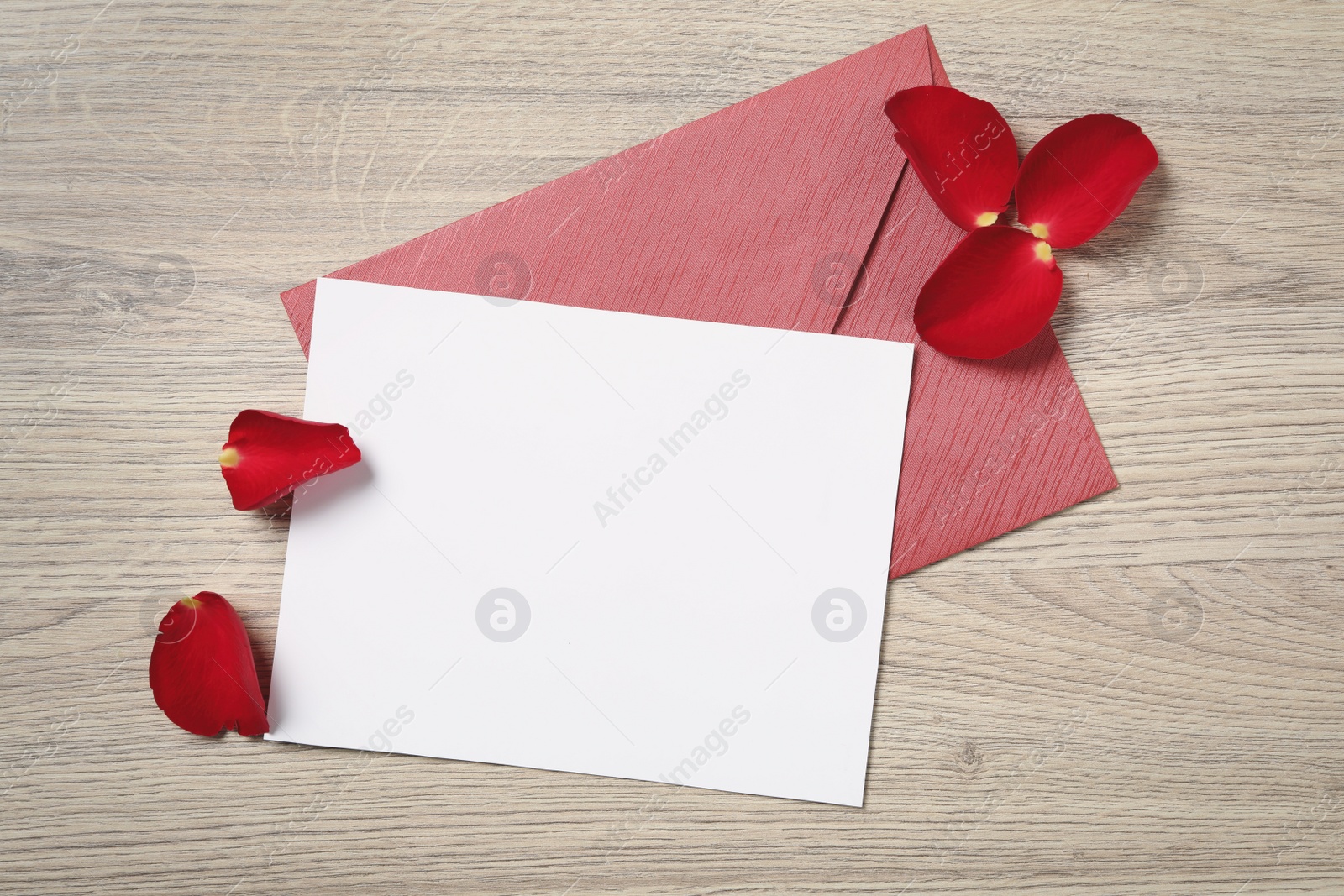 Blank greeting card, envelope and rose petals on wooden table, flat lay. Valentine's day celebration Photo of Blank greeting card, envelope and rose petals on wooden table, flat lay. Valentine's day celebration