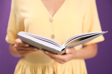 Young woman with book on purple background, closeup Photo of Young woman with book on purple background, closeup